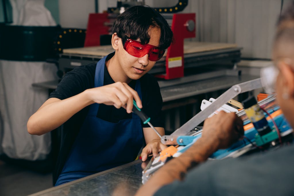 Young technician wearing safety goggles working with machinery in an industrial setting.